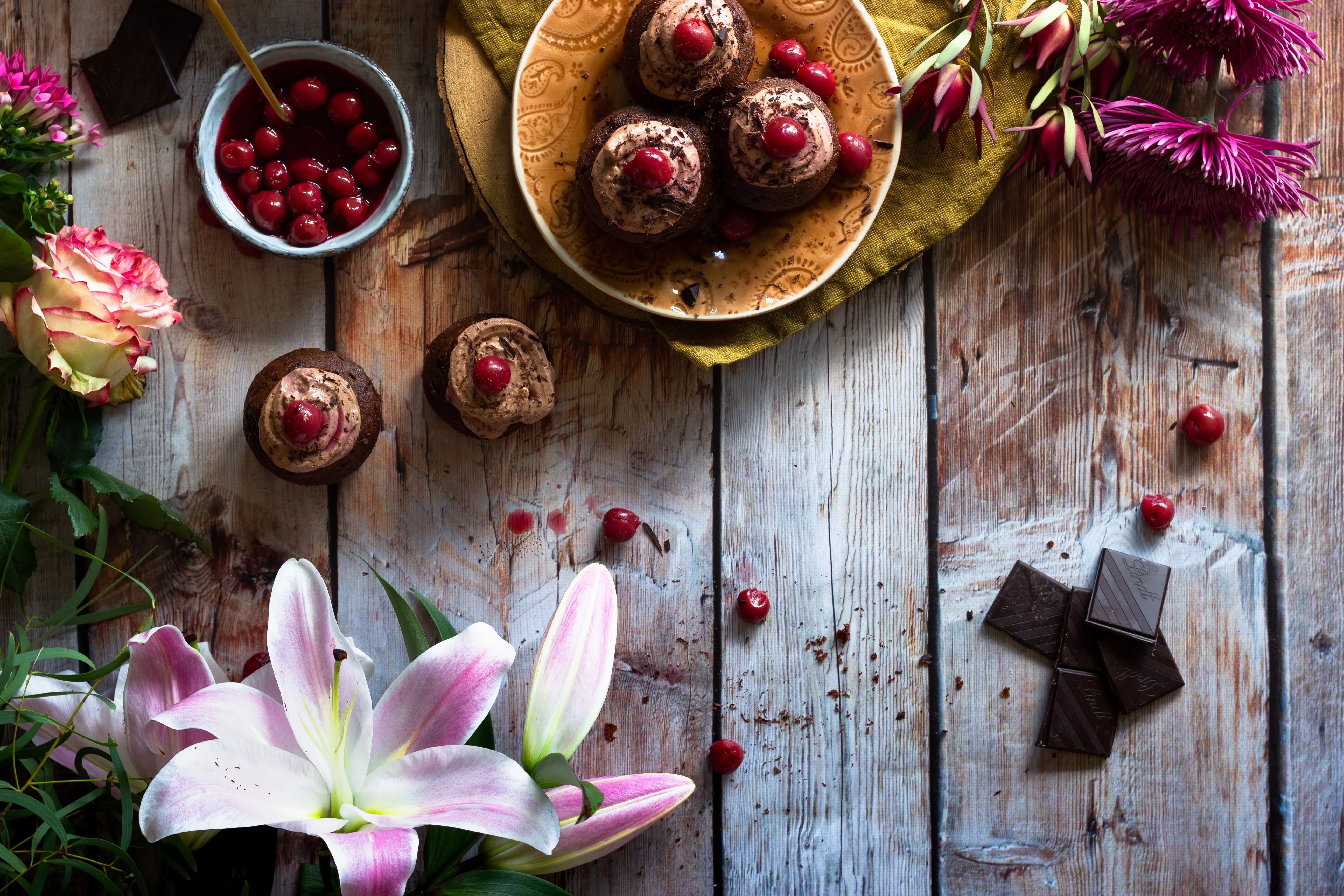 Chocolate-topped holiday desserts, cranberries and flowers laid out on a wooden table