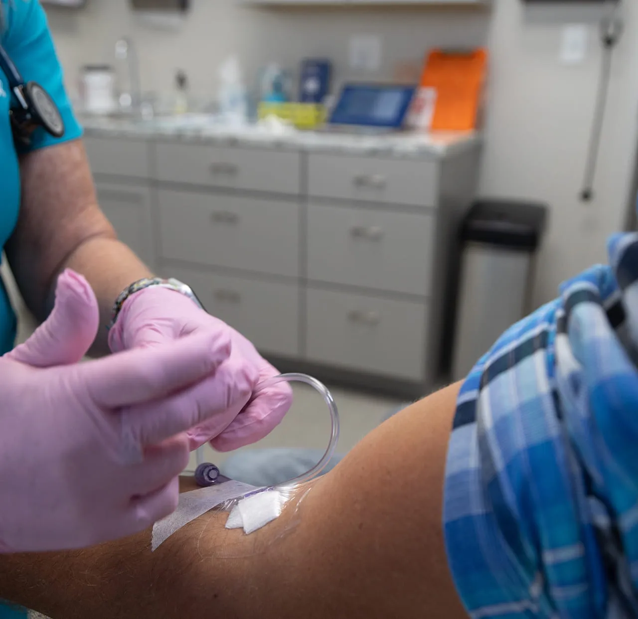 A gloved clinician drawing a blood sample from a patient’s arm
