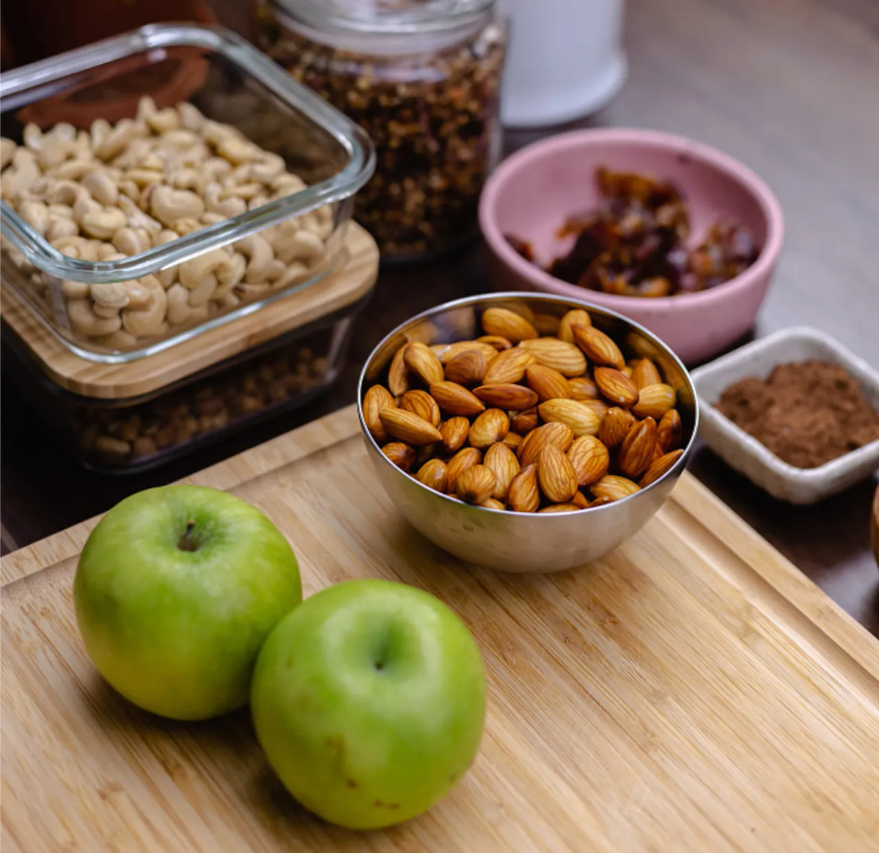 Apples, almonds and prepared snacks laid out on a wooden board